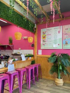 the inside of a restaurant with pink walls and purple stools