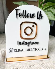 a white and gold instagram sign sitting on top of a table