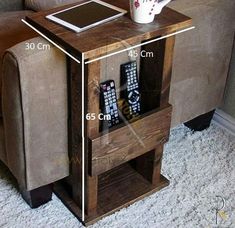 a small wooden table with remotes on it and a coffee cup sitting on top