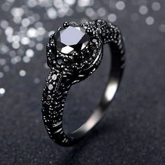 a black diamond ring on a table with silver glitters around it and the center stone is