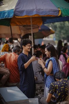 a man and woman standing under an umbrella talking to each other while others look on