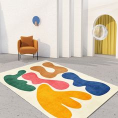 a colorful rug in the middle of a room with a chair and wall hangings