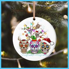 a christmas ornament hanging from a tree with three skulls wearing santa's hats