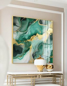 a painting on the wall above a console table in a room with white walls and gold accents