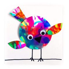 a paper plate with a colorful bird on it's face and eyes painted in bright colors