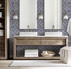 a bathroom with blue and white tiles on the wall, two sinks and mirrors above them