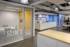 an office with white and yellow accents, glass partitions, desks and chairs