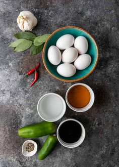 eggs, peppers, and seasoning in bowls on a gray surface next to garlic