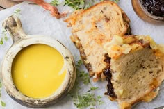 bread and butter sit on top of a piece of paper next to a jar of mustard