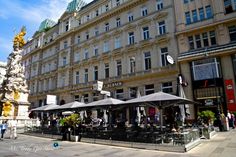 people are sitting at tables in front of an old building with many windows and balconies