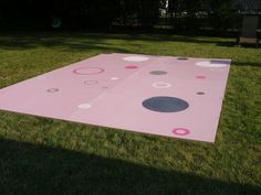 a pink area rug sitting on top of a green grass covered field with circles and dots