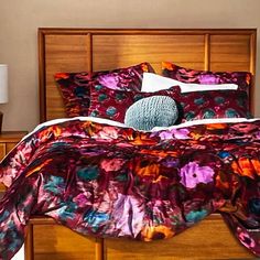 a bed with a colorful comforter and pillows on it's headboard in a bedroom