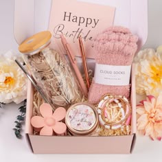 a pink box filled with lots of crafting supplies next to some flowers and candles