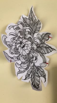 a drawing of flowers and leaves on a piece of paper that is taped to the wall