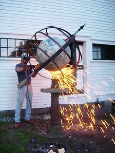 a man is working on an object in front of a building with sparks coming from it