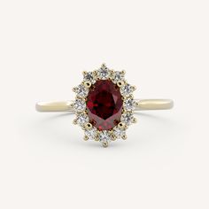 a ring with a red stone surrounded by white diamonds on the sides and yellow gold band