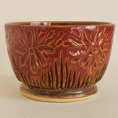 a brown bowl with flowers on it sitting on a table