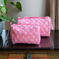 two pink bags sitting on top of a table next to a potted plant