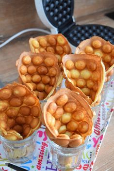 four cups filled with nuts sitting on top of a table next to a waffle iron