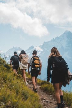 several people hiking up a hill with mountains in the background