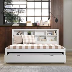 a white daybed with drawers underneath it in a living room next to a window