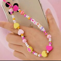 a person holding a cell phone with a beaded bracelet on it