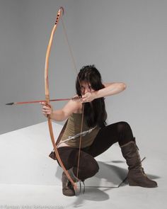 a woman kneeling down with a bow and arrow