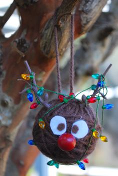 a christmas ornament hanging from a tree with lights on it's head