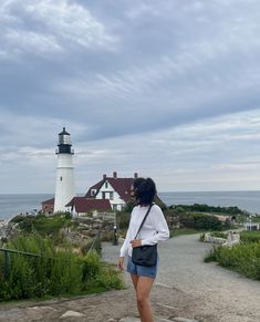 a woman standing in front of a light house