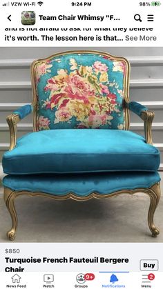 a blue velvet chair with gold trimming and flowers on the back, sitting in front of a striped wall