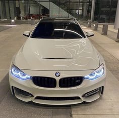 the front end of a white bmw car parked in an empty parking lot at night