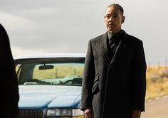 two men standing next to each other in front of a car