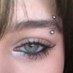 a woman with piercings on her eyes looking at the camera