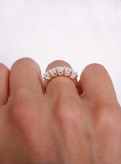 a person's hand holding a ring with three small diamonds on the middle of it