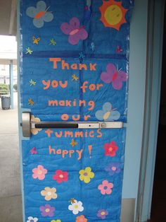 a blue door decorated with flowers and the words thank you for making our tummies happy