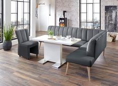 a white table with grey chairs around it in front of large windows and wood flooring