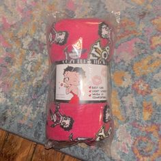 two pink socks sitting on top of a wooden floor next to a plastic bag filled with cartoon characters