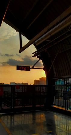 an empty train station with the sun setting in the background