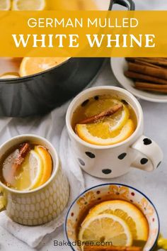 two mugs of german mulled white wine with lemon slices and cinnamon on the side