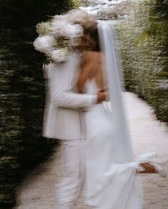 a bride and groom embracing each other outside