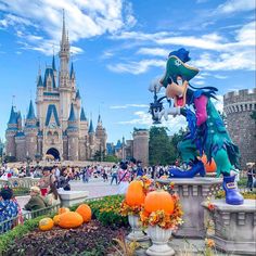 people are walking around in front of the castle at disney world with pumpkins on the ground