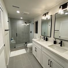 a bathroom with two sinks, a toilet and a walk in shower