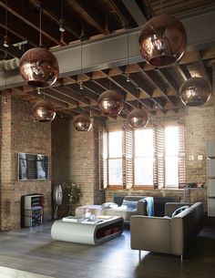 an industrial living room with exposed brick walls and ceiling lights hanging from the ceiling, along with modern furniture