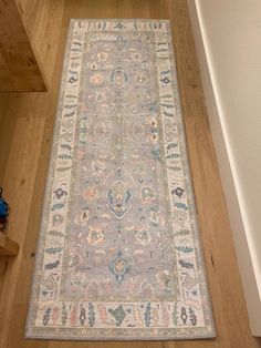 a large rug on the floor in a room with wood floors and white walls, along with wooden stairs