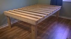 a wooden bed frame sitting on top of a hard wood floor next to a window