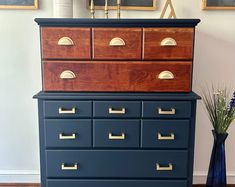 a blue dresser with gold handles and drawers in a room next to two framed pictures on the wall