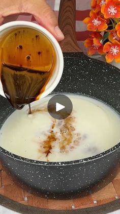 a person pours milk into a bowl with orange flowers in the backgroud