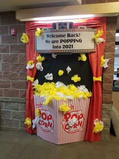 a welcome back sign in front of two popcorn buckets with yellow flowers on them