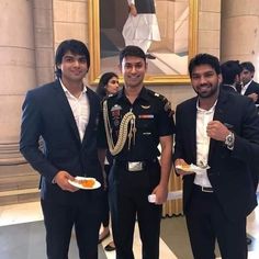 three men in suits are holding plates and posing for the camera while one man holds food