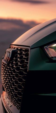 the front end of a green car at sunset